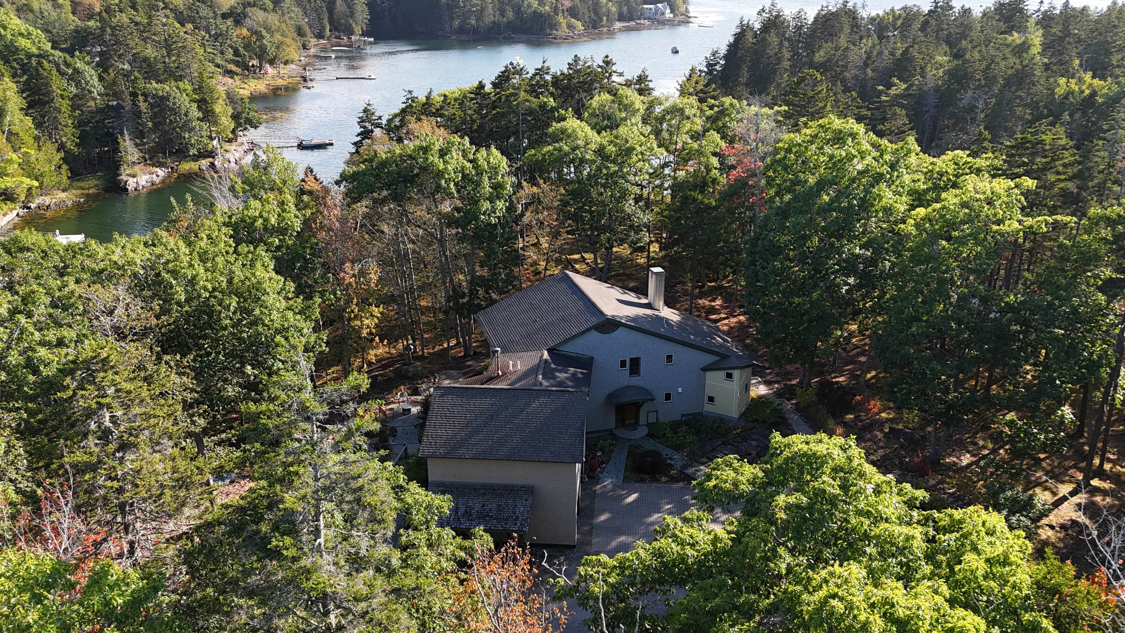 A house surrounded by dense forest with a view of a lake.