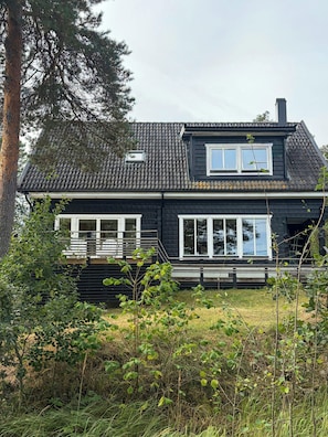Et toetagers hus med mørk facade, hvide vinduesrammer og et tagdækket med tagsten.