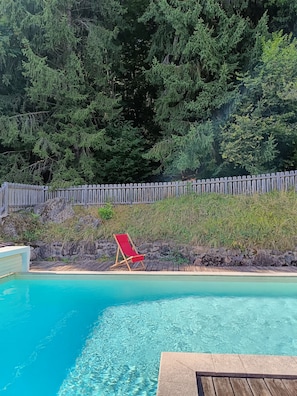 A clear blue pool with a wooden deck and a red lounge chair. - Chalet for rent, with breathtaking views and accommodations for up to 15 guests. (Ugine)