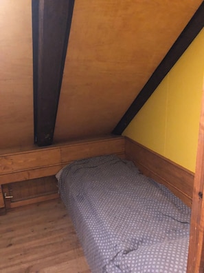 A small, single-bed room with a sloped ceiling, wooden beams, and a yellow wall. - Chalet for rent, with breathtaking views and accommodations for up to 15 guests. (Ugine)