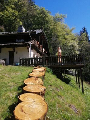 A traditional chalet with a wooden deck and a stone wall. - Chalet for rent, with breathtaking views and accommodations for up to 15 guests. (Ugine)