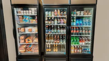 Three beverage vending machines stocked with various drinks and snacks.