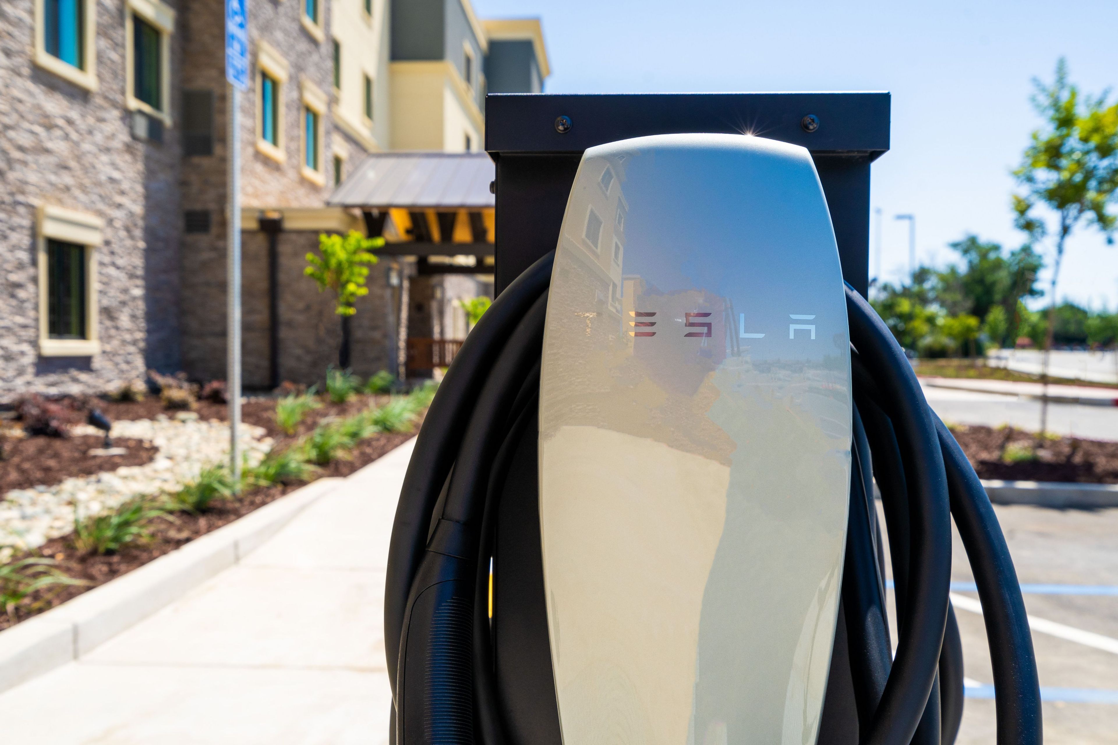 Una estación de carga de Tesla con vista despejada del edificio circundante y el paisajismo.