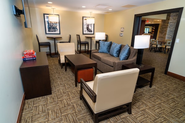 A hotel lobby with a sofa, chairs, a coffee table, a desk, and a lamp.