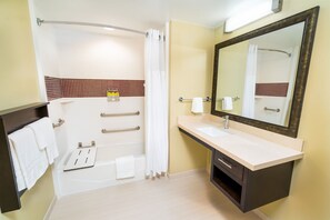 Un baño moderno con bañera, lavamanos y un espejo grande.