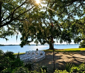 A circular outdoor seating area with white chairs arranged around a central focal point, overlooking a body of water.
