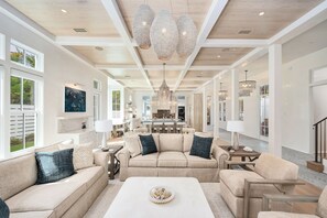A spacious living room with a large sofa set, a coffee table, and a dining area in the background. - Grace By The Sea|Easy Beach Access|Private Pool|Golf Cart (Seacrest Beach)