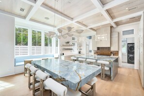 A modern kitchen with a large marble island, pendant lighting, and a view of the outdoors. - Grace By The Sea|Easy Beach Access|Private Pool|Golf Cart (Seacrest Beach)