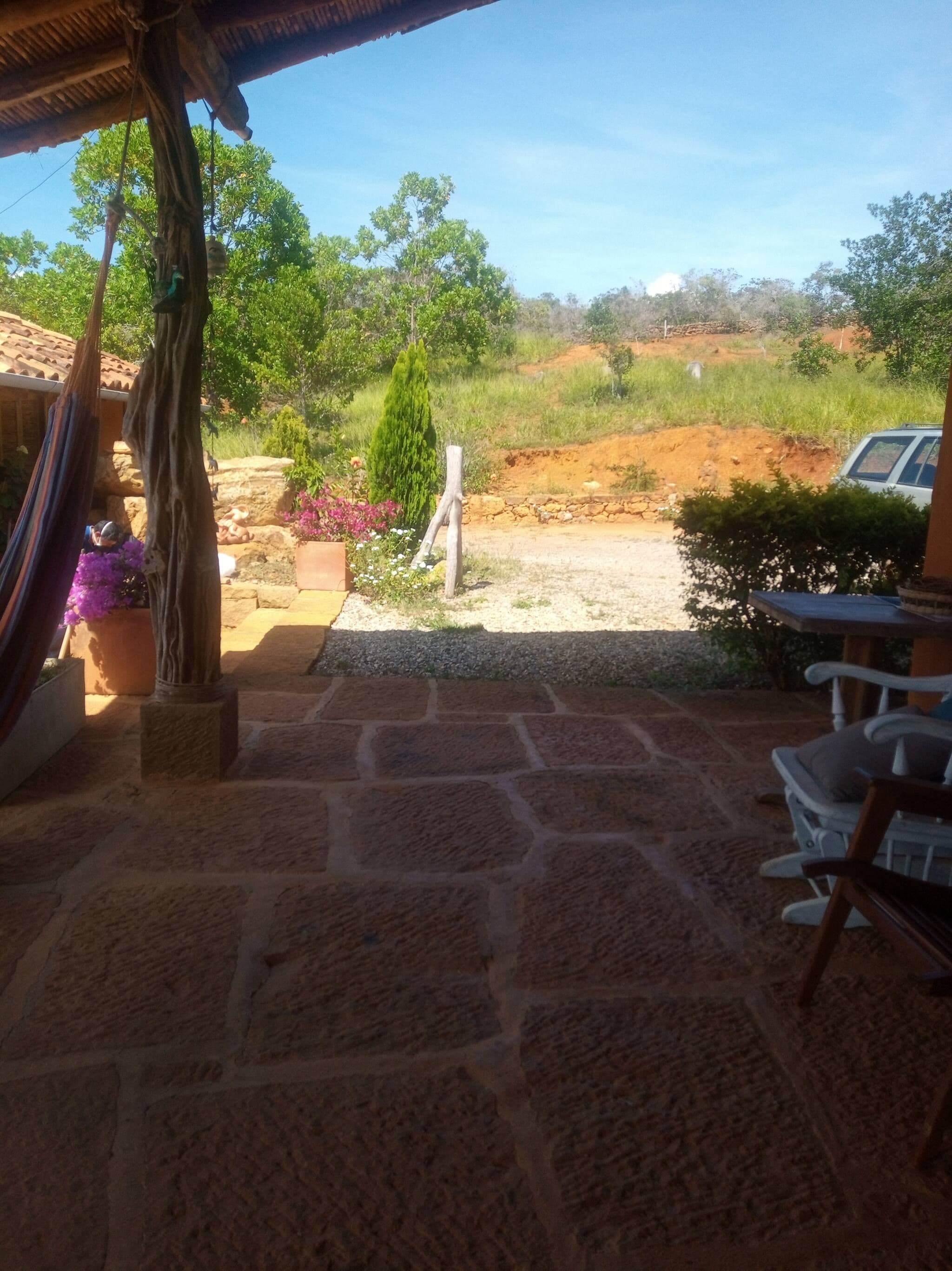 Um pátio de pedra com rede, mobiliário de exterior e vista para a paisagem natural.
