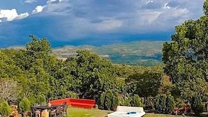 Piscina com vista para um edifício de telhados vermelhos e vegetação exuberante ao fundo.