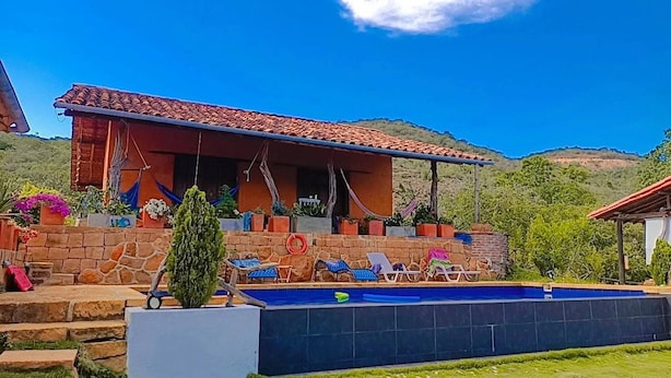 Uma casa com piscina, degraus de pedra e área de varanda com espreguiçadeiras.