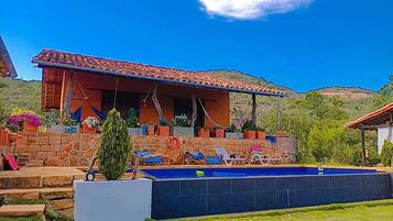 A house with a swimming pool, stone steps, and a patio area with lounge chairs.