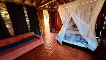 Una habitación con cama bajo dosel, un sofá y techo de madera.