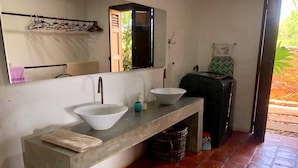 Casa de banho com uma pia grande, espelho e porta-toalhas.