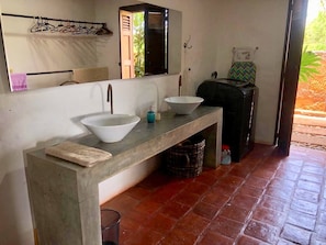 Une salle de bain avec un grand lavabo, un miroir et un porte-serviettes.