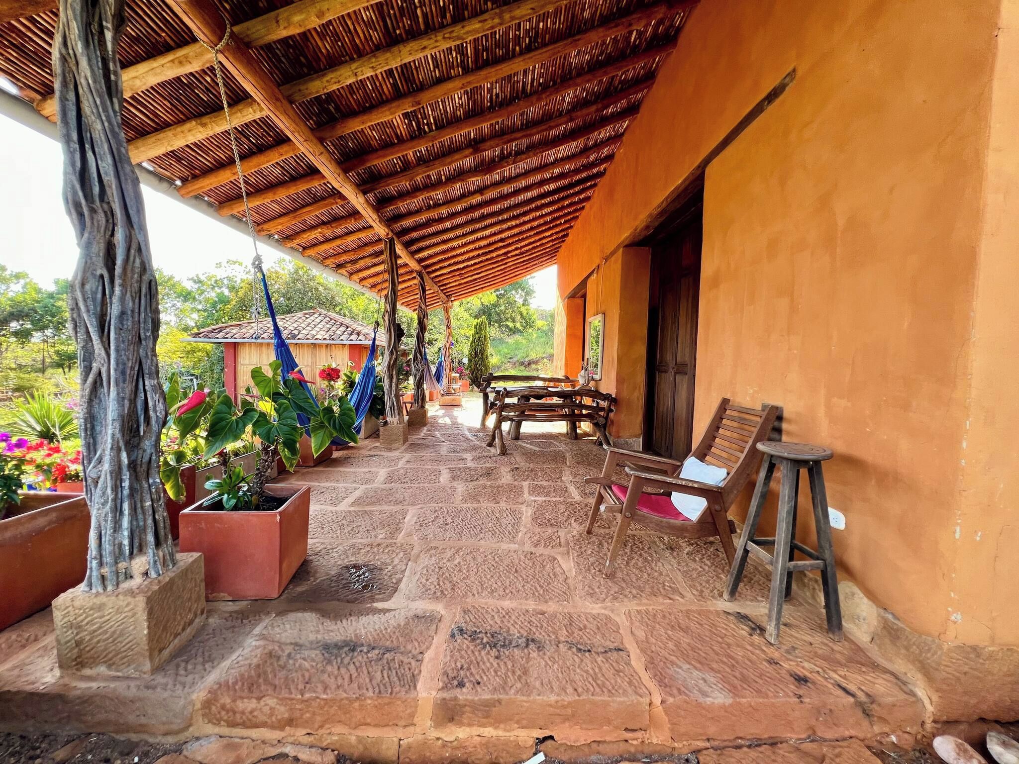 A covered outdoor area with a wooden ceiling, stone flooring, and potted plants.