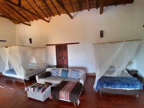 A room with two beds, each with a canopy, a sofa, and a small table. - Casa upa con Piscina Climatizada (Barichara)