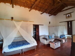 A room with a bed under a mosquito net, a sofa with cushions, and a wooden ceiling. - Casa upa con Piscina Climatizada (Barichara)