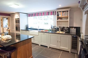 Een moderne keuken met een centraal eiland, inbouwapparatuur en een raam met gestreept gordijn.
