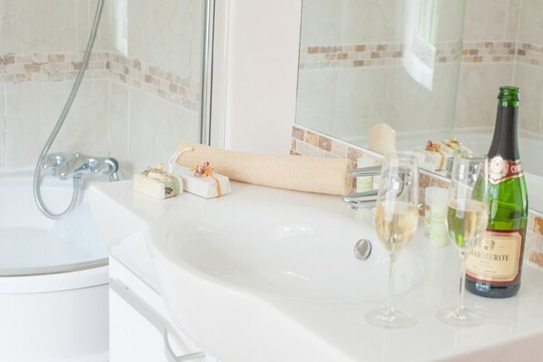 A bathroom with a white sink, a bottle of champagne, and two glasses on the counter.