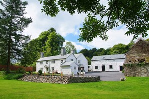 A white stone building with a stone wall and a grassy lawn.
