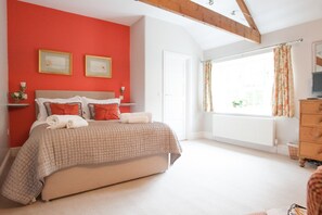 A bedroom with a bed, a window with curtains, a dresser, and a radiator.