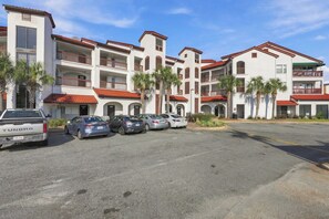 Ein mehrstöckiges Hotel mit Parkplatz, erkennbar an seinem roten Ziegeldach und den weißen Wänden.