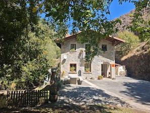 A stone building with a red roof, a paved driveway, and a wooden fence.