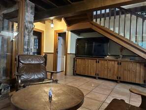 A living room with a leather chair, a wooden coffee table, and a television on a wooden cabinet.