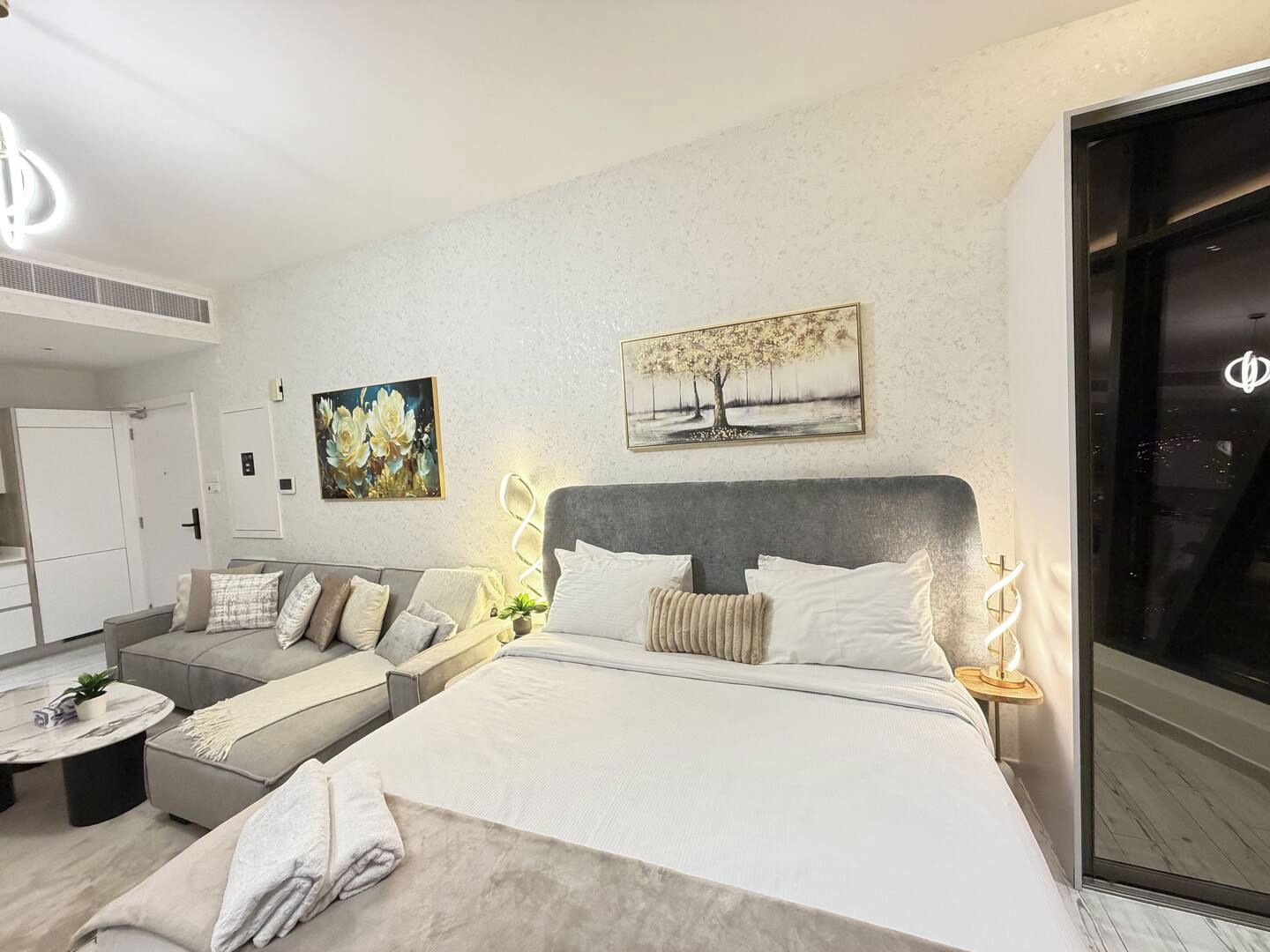 A modern bedroom with a bed, a sofa, a coffee table, and artwork on the walls.