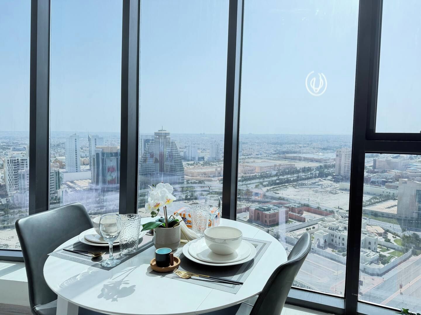 A dining table with a view of a cityscape through large windows.