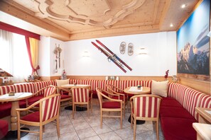 Ein Restaurant mit Holzbänken und -tischen, Skiausrüstung an der Wand und einem Gemälde mit Bergblick.