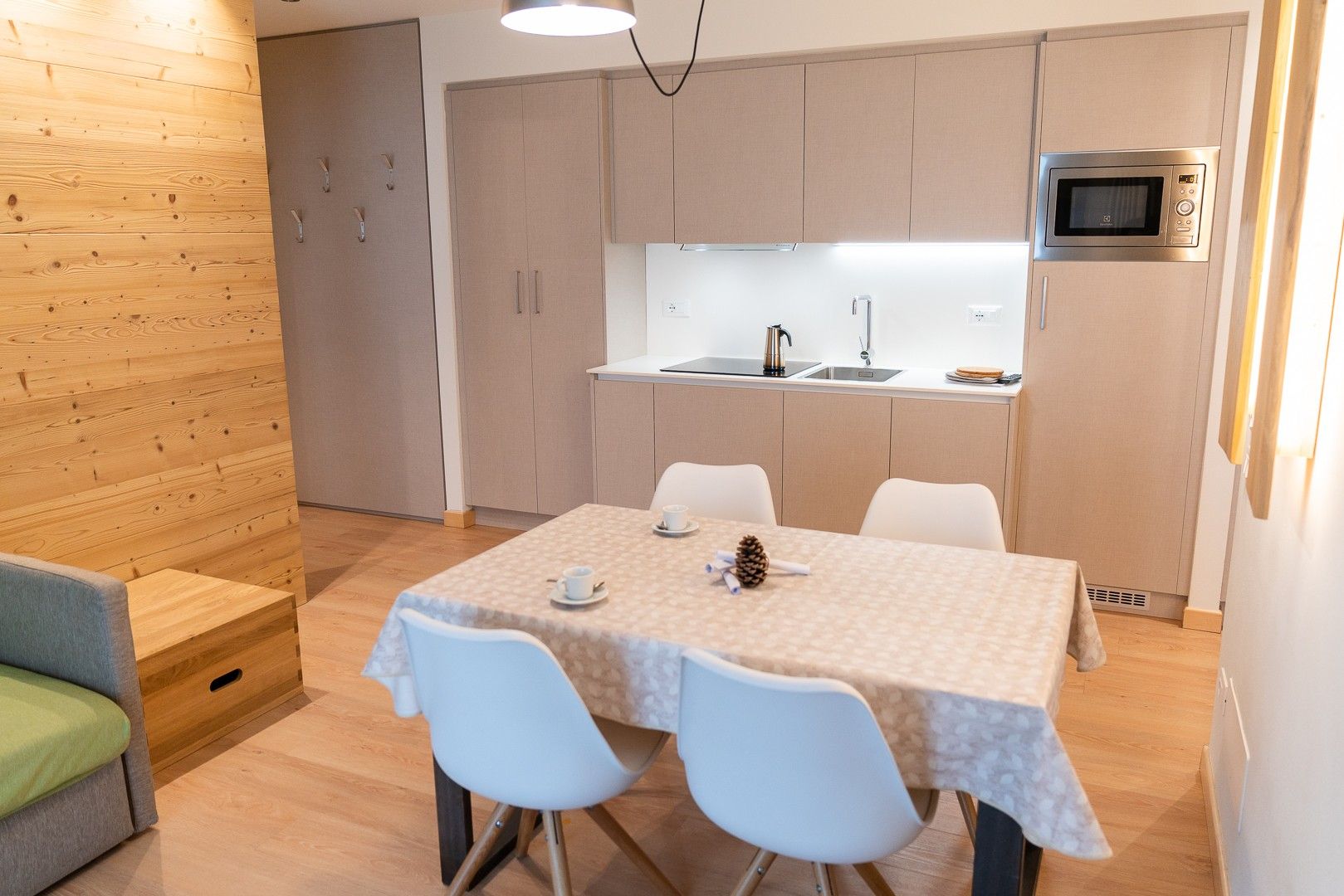 Een knus woongedeelte met een eethoek, kitchenette en een zithoek met een bank.