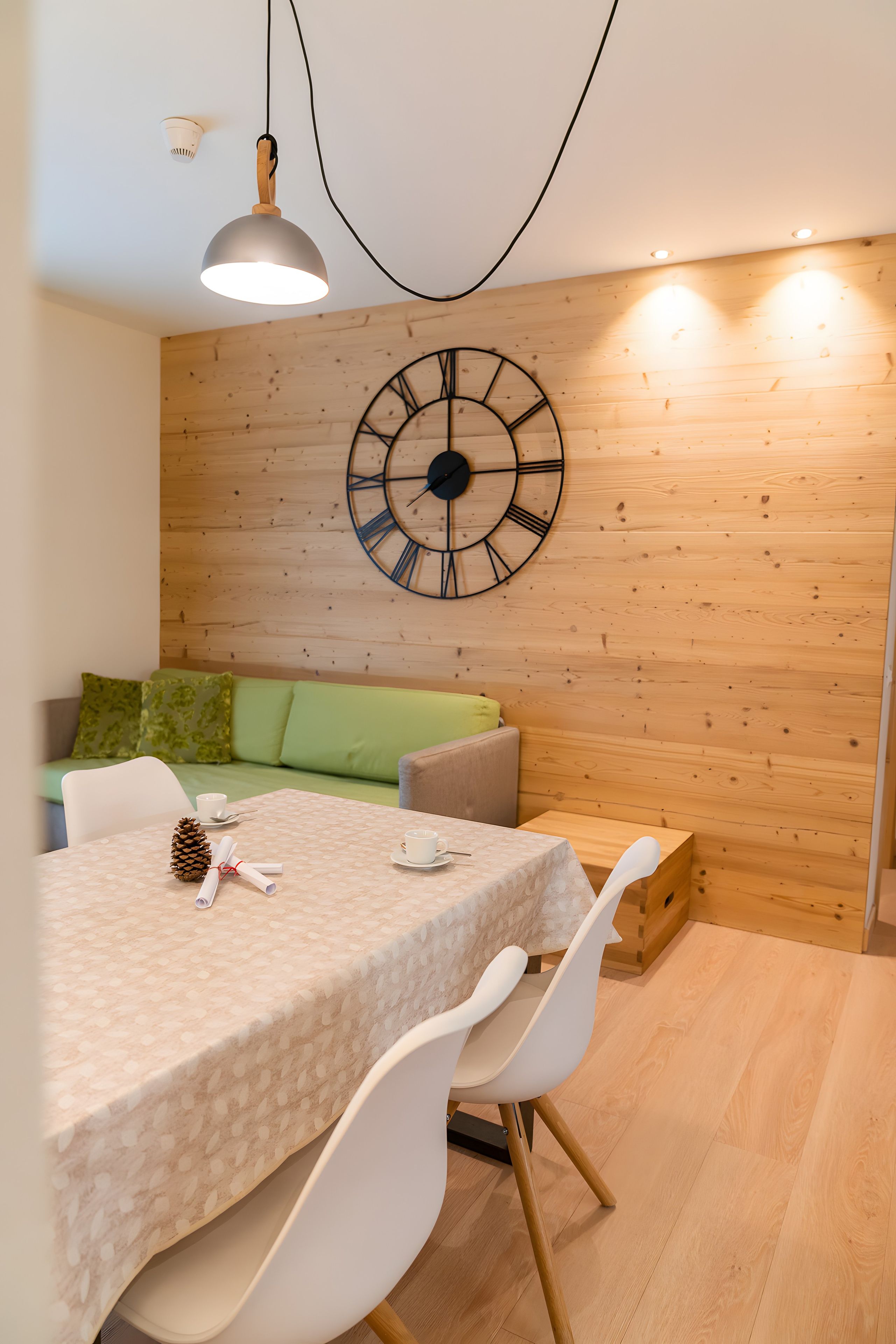 Ein Essbereich mit einer runden Wanduhr, einem Tisch mit Stühlen und einer Holzwand.