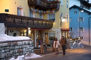 Ein Hotel mit einer Stein-Fassade, einem Balkon mit Lichterketten und einem Weihnachtsbaum.