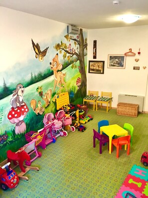 A children's playroom with a mural, toys, and furniture.