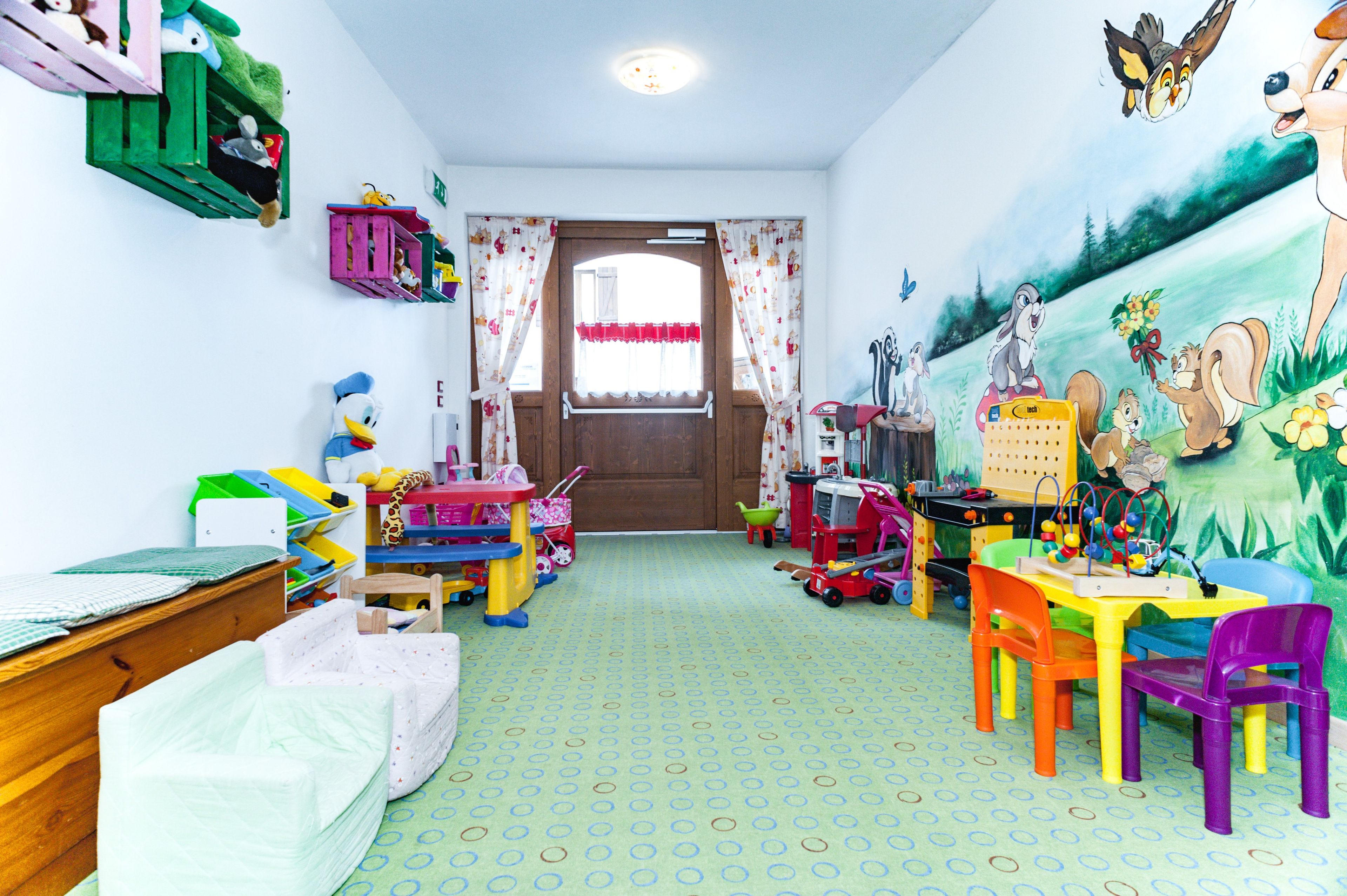 Ein Kinderzimmer mit Spielzeug, einem Schreibtisch und einer Wandmalerei.