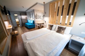 Una camera d'albergo con un letto, una scrivania, una sedia, un divano e un pannello di legno.