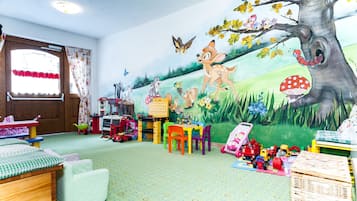 Een kinderspeelkamer met een muurschildering, speelgoed en een groen tapijt.
