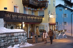 Un hotel con facciata in pietra, un balcone decorato con luci e un albero di Natale.
