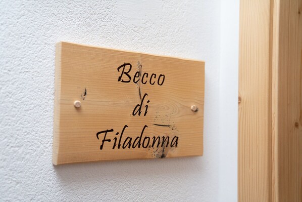 Un cartello di legno con la scritta 'Becco di Filadonna' fissato a una parete.