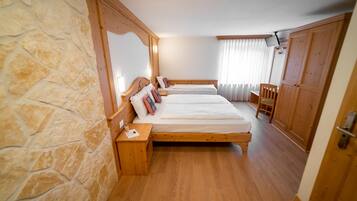 Un dormitorio con dos camas de madera, paredes de piedra, un armario de madera y una silla.