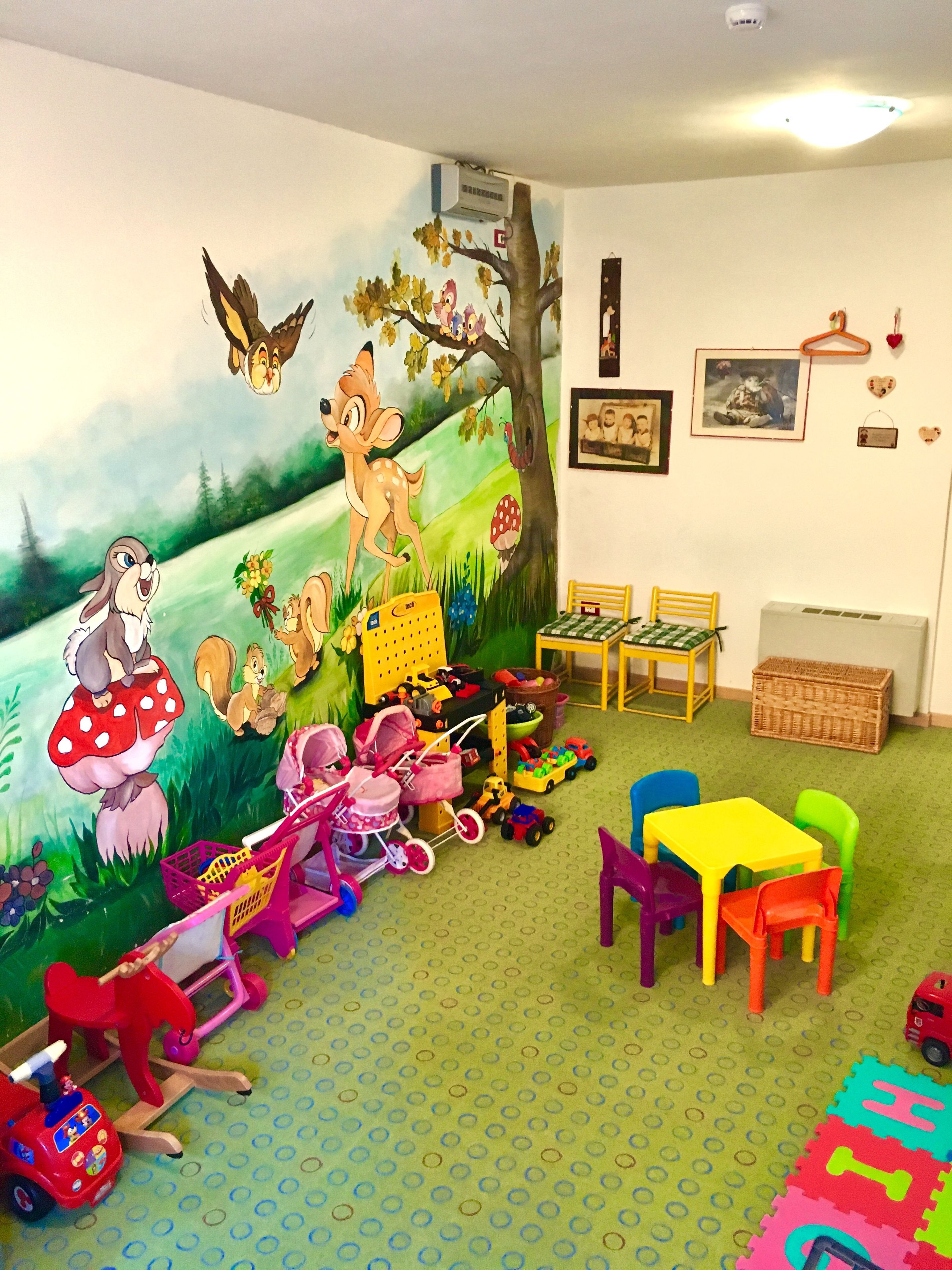 Ein Spielzimmer für Kinder mit Wandmalerei, Spielzeug und Möbeln.