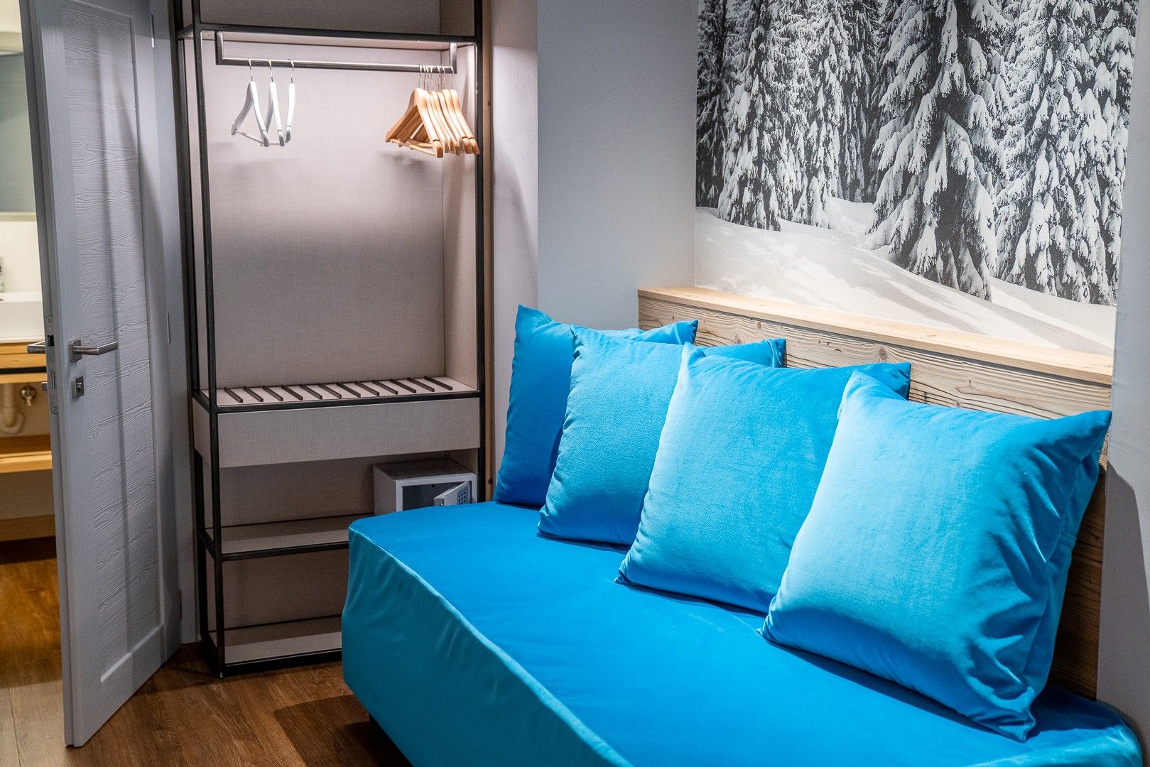Una habitación con cama, armario y estante fijado a la pared.