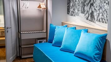 Una habitación con cama, armario y estante fijado a la pared.