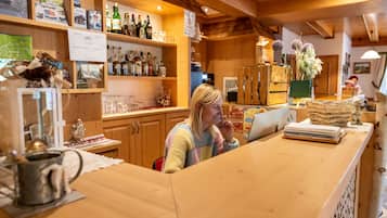 Een houten interieur met een bar, flessenkasten en een persoon achter de toog.