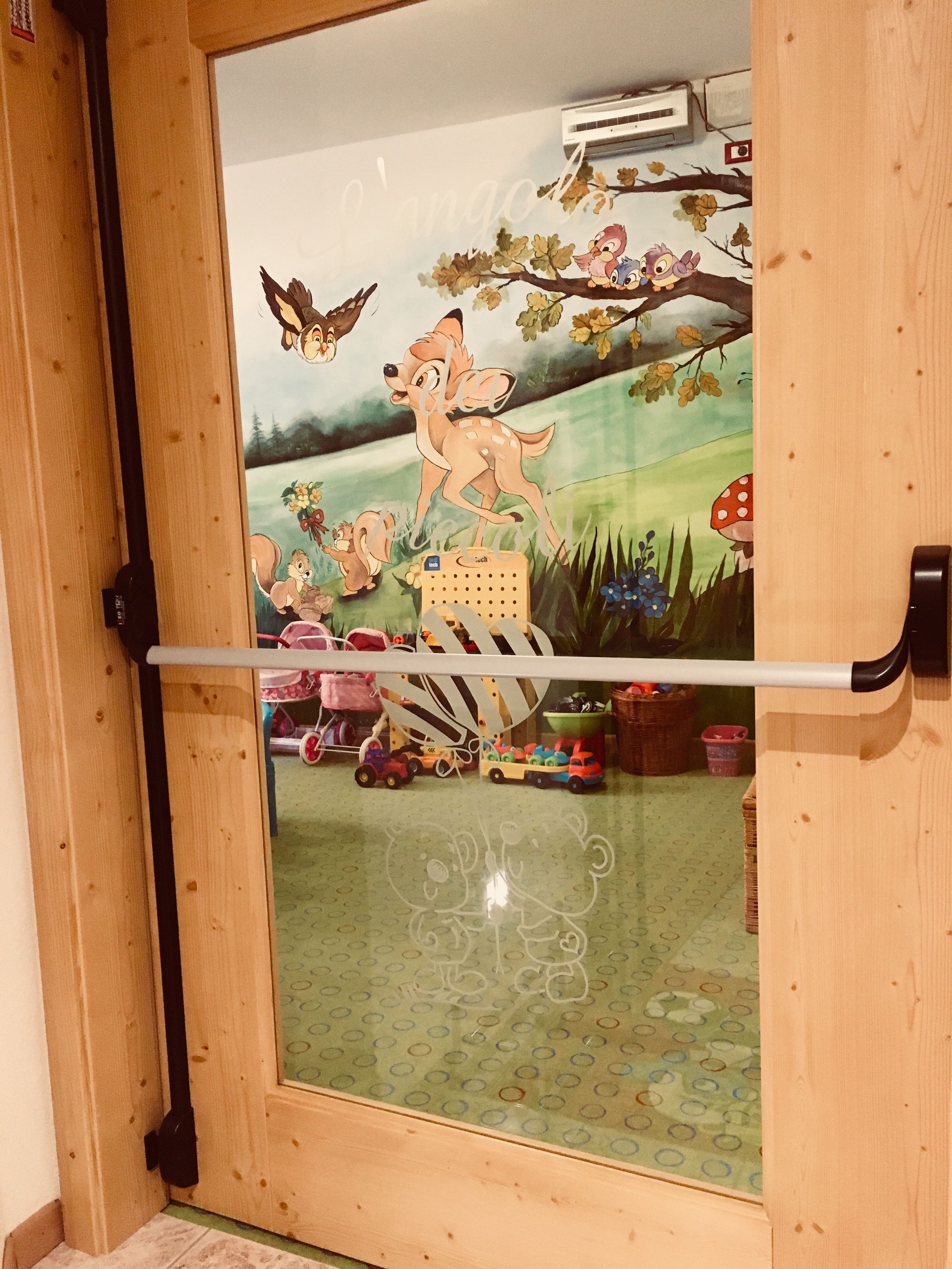 Een houten deur met een ruit, waarop een cartoon herten en een boslandschap afgebeeld zijn.
