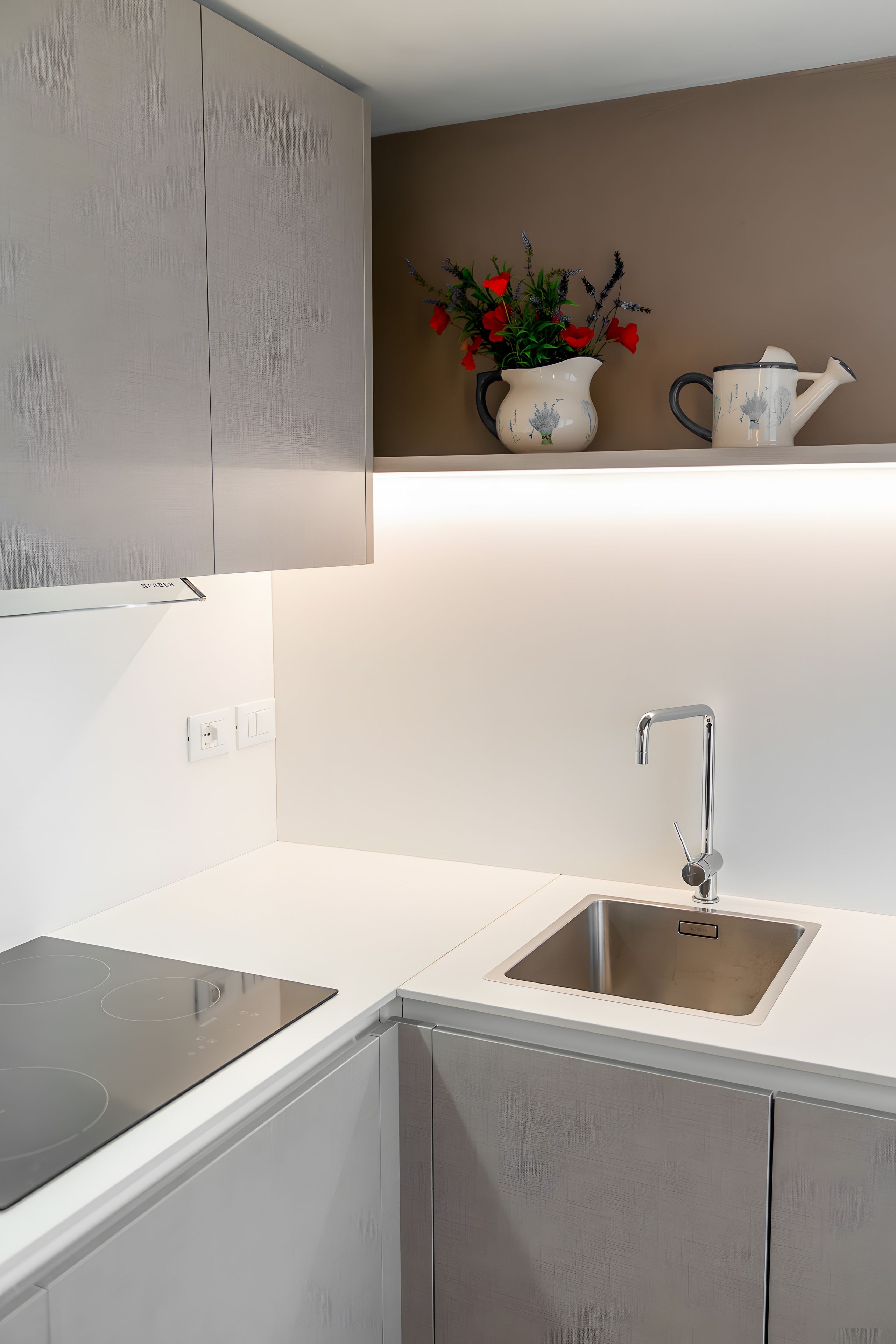 Een moderne keuken met een dubbele spoelbak, een inbouwfornuis en een decoratieve vaas met bloemen op het aanrecht.