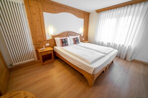 Camera da letto con struttura in legno, un letto matrimoniale, lampade sui comodini e un termosifone.