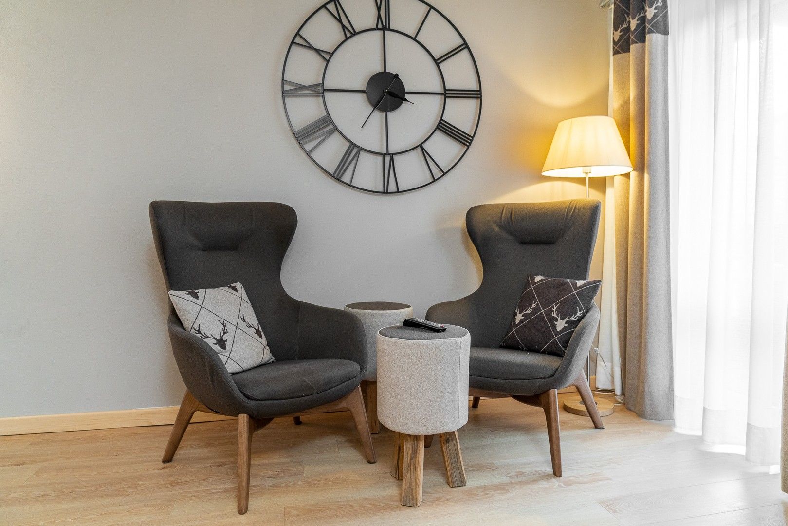 A modern living room with two armchairs, a small table, and a large wall clock.